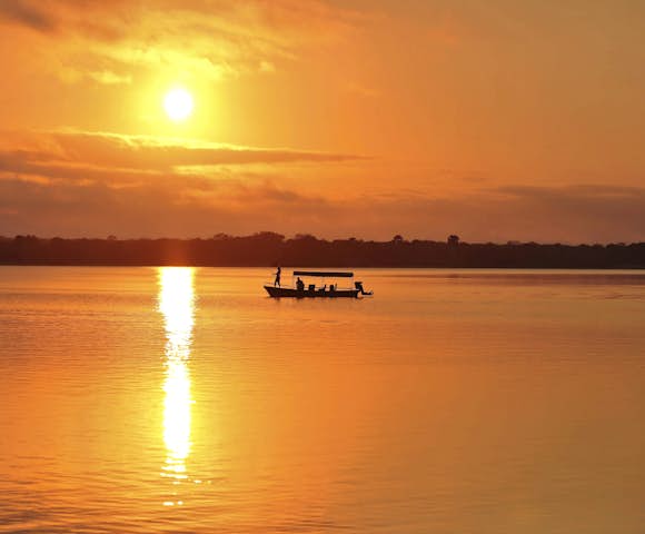 Sunset over lake with boat on river at Selous Game Reserve, Tanzania