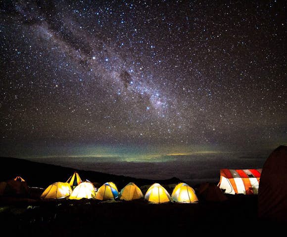 Night sky above glowing tents on Kilimanjaro hike in Tanzania